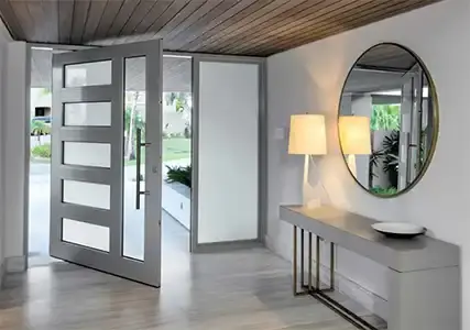 Open pivot entry door with frosted glass panels seen from the foyer